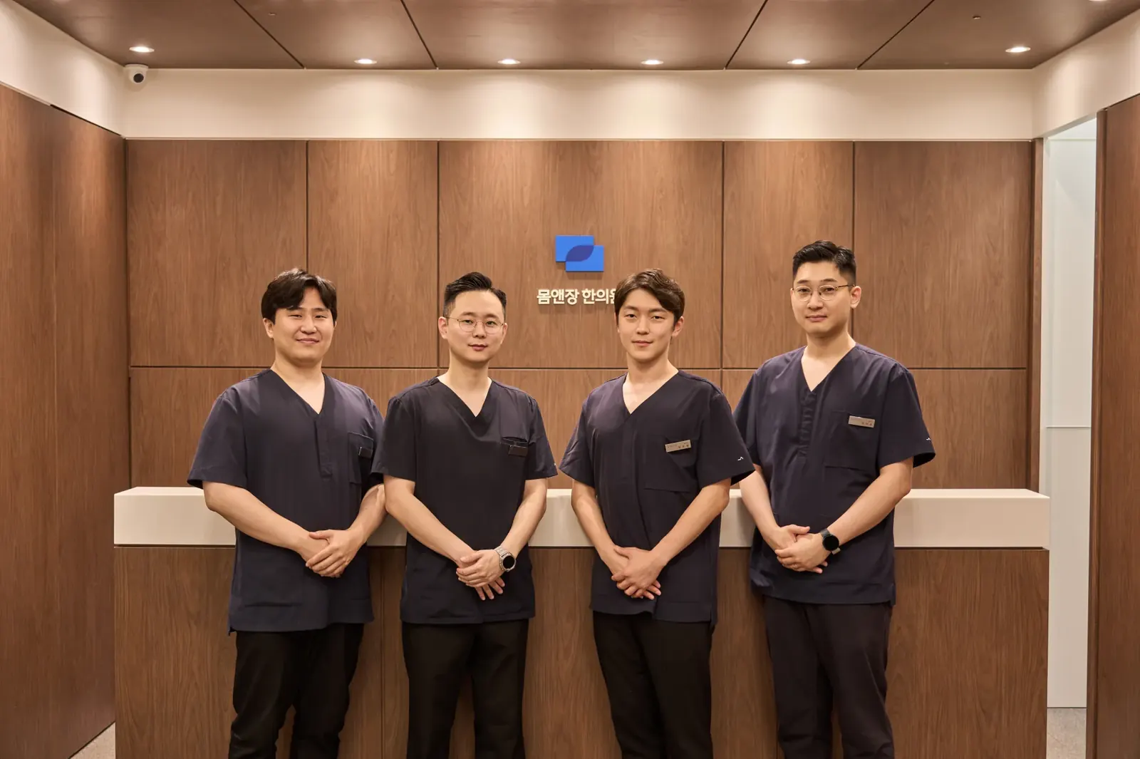 군포 산본 몸앤장한의원 로고 앞에 선 의료진 4인 단체 사진