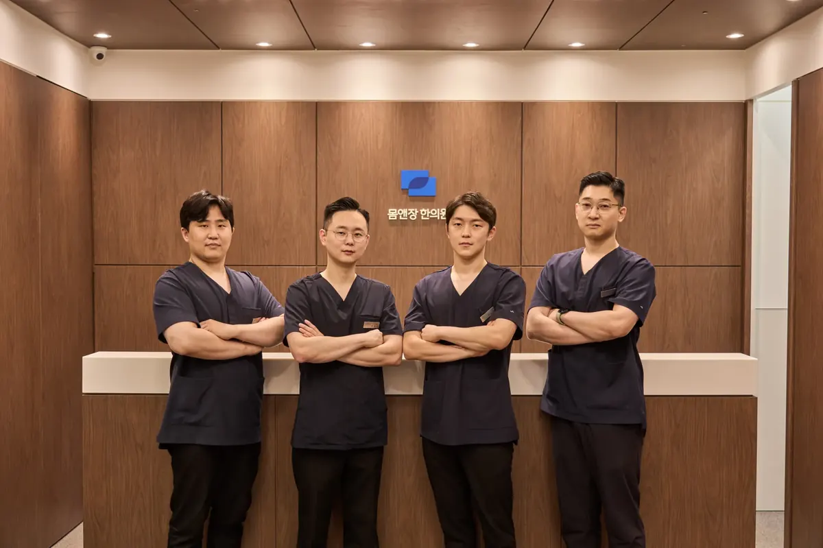 군포 산본 몸앤장한의원 의료진 4인이 접수 데스크 앞에 서 있는 모습